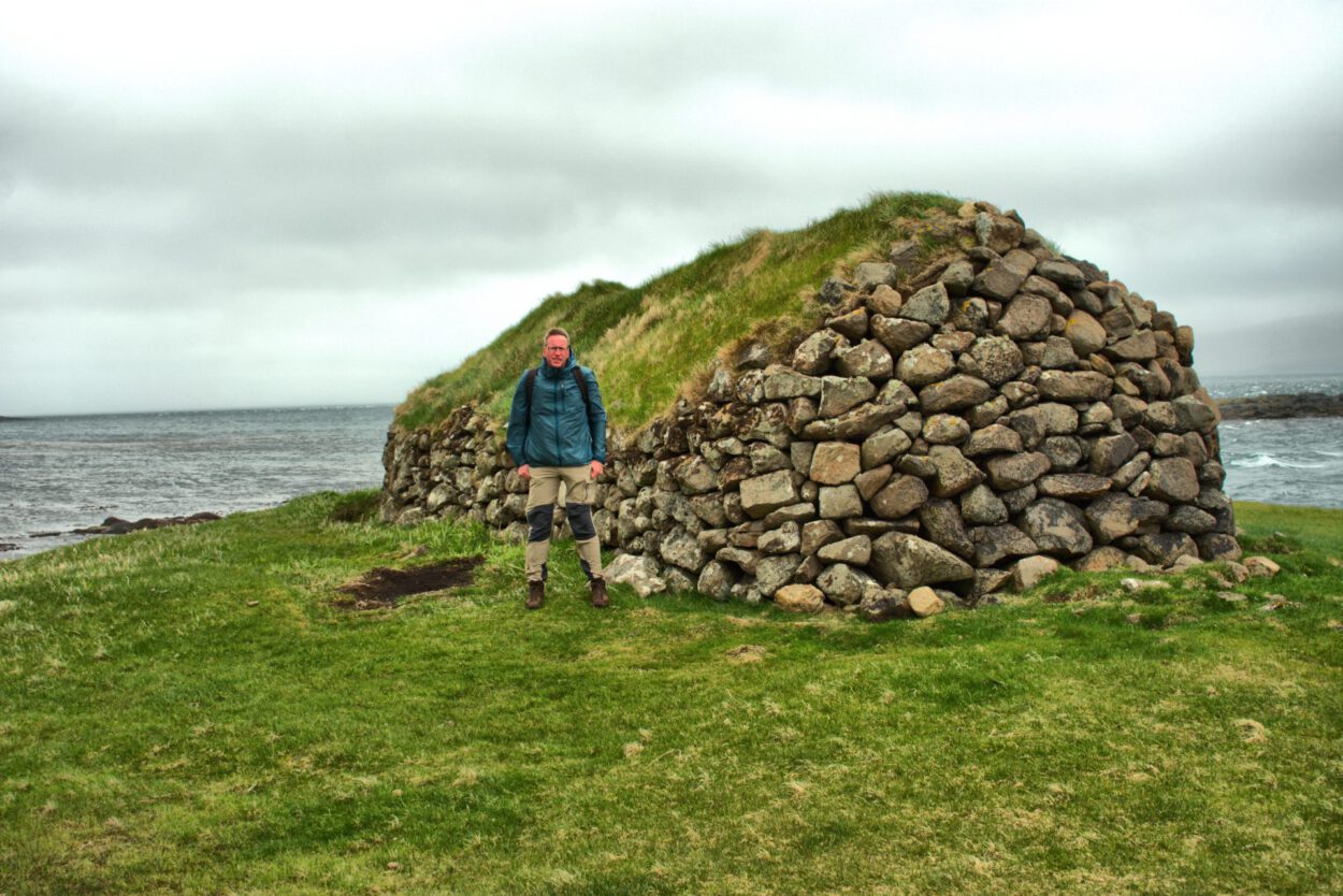 Ein Mann steht vor einer Steinstruktur in der Nähe des Ozeans.