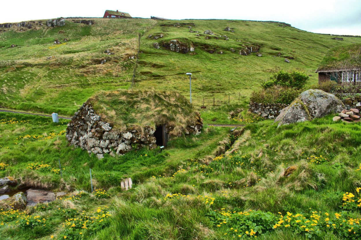 Ein grasbewachsener Hügel mit einer Hütte darauf.