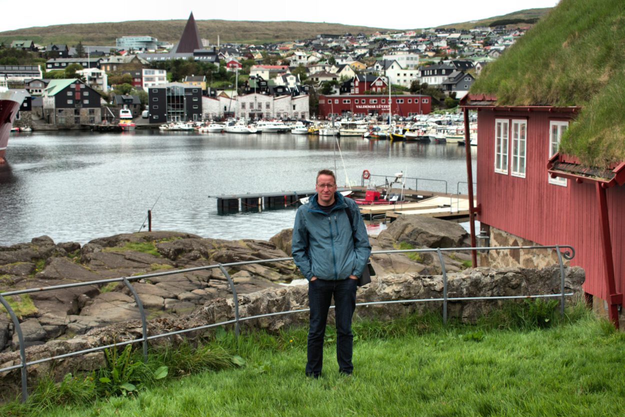 Ein Mann steht vor einem Gebäude mit grünem Dach.