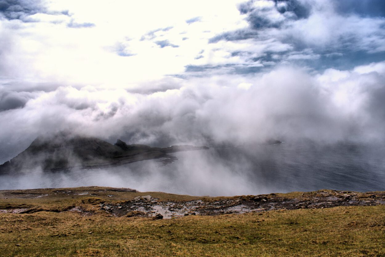 Ein Blick auf einen mit Wolken bedeckten Hügel und ein Gewässer.