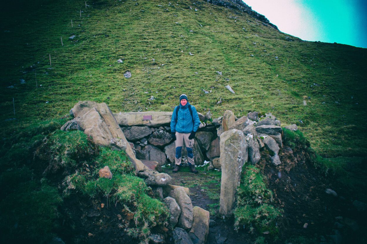 Eine Person steht vor einer Felsformation in Schottland.