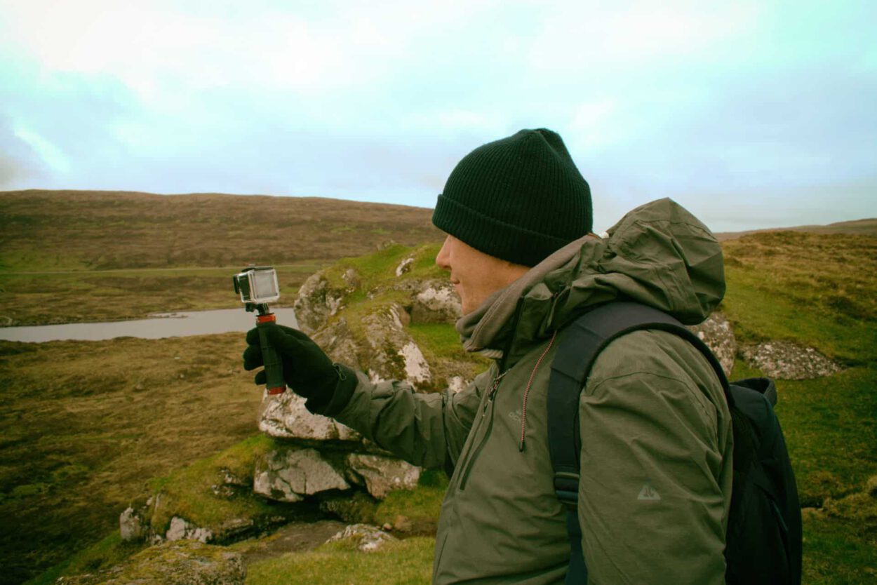 Ein Mann hält eine GoPro-Kamera auf einem Feld.