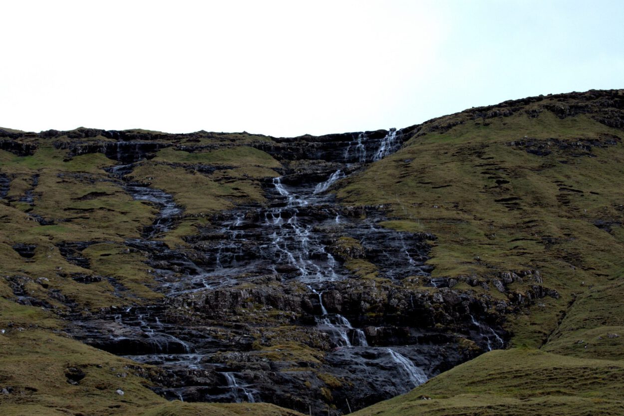 Ein Wasserfall inmitten eines grasbewachsenen Hügels.