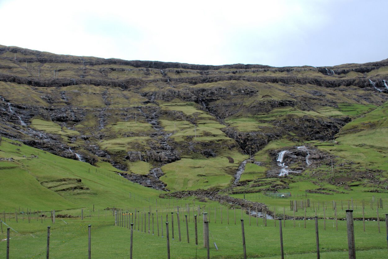 Ein grasbewachsener Hügel mit einem Wasserfall.
