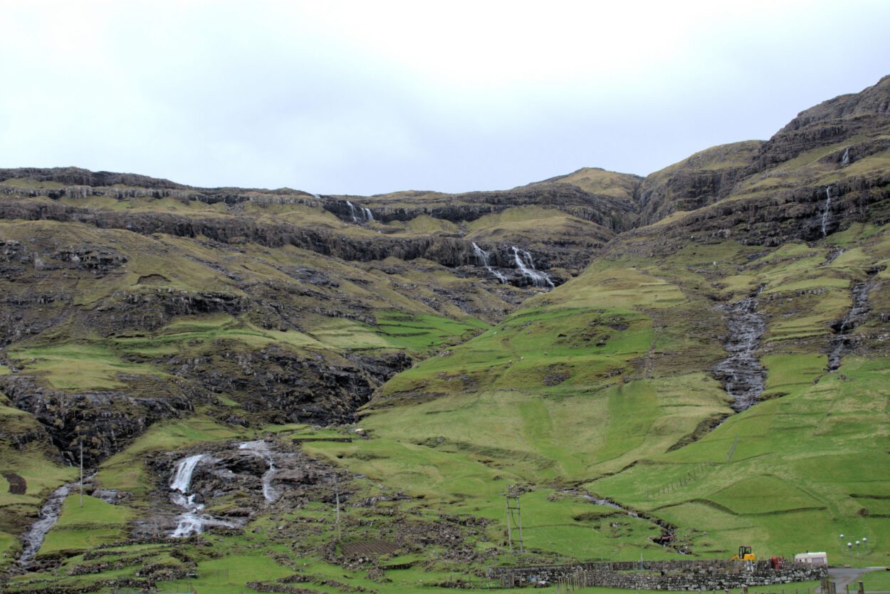 Ein grüner Hügel mit einem Wasserfall.