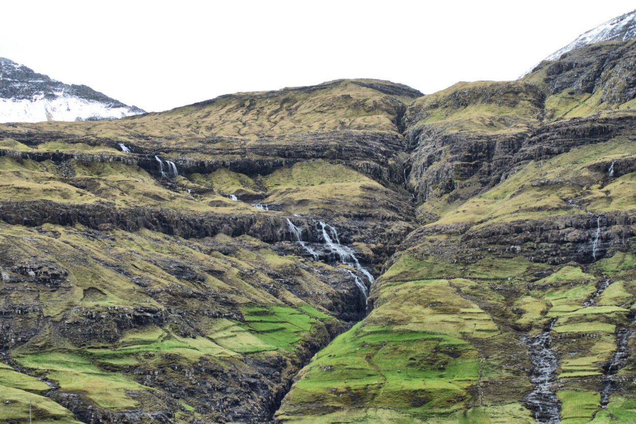 Ein grüner Berg mit einem Wasserfall.