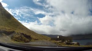 Ein Auto fährt eine Straße entlang mit Bergen im Hintergrund, aufgenommen in einem MP4-Video.