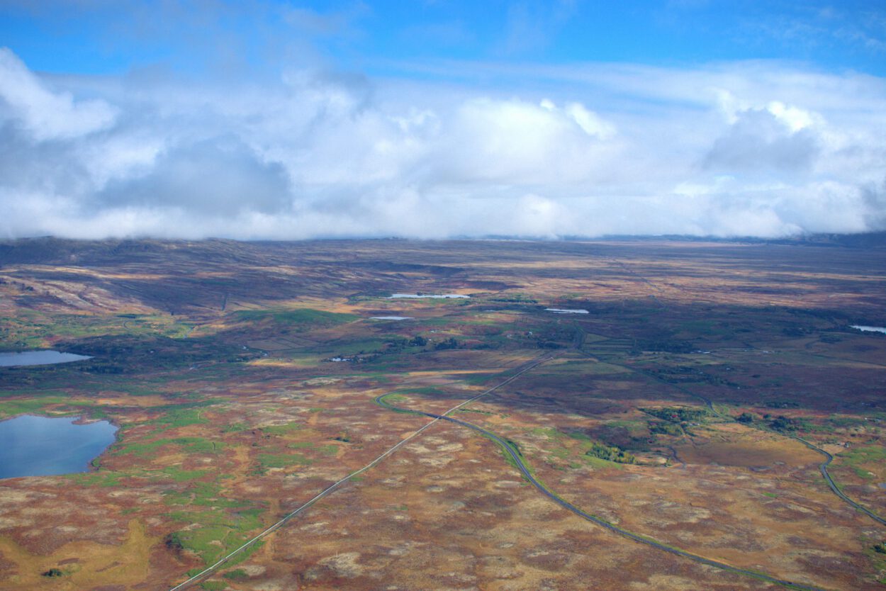 Eine Luftaufnahme eines braunen Feldes mit einem See in der Ferne.
