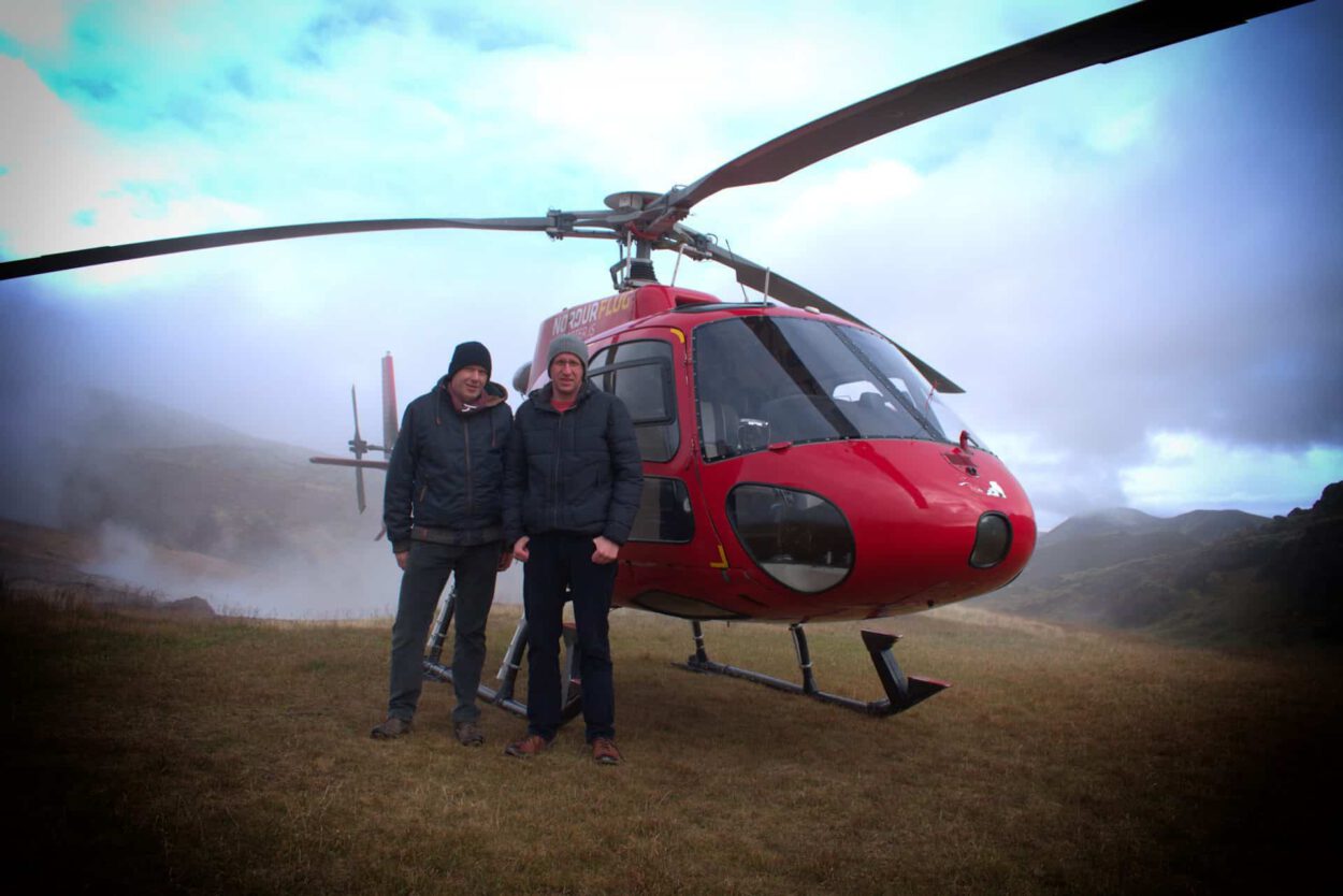 Zwei Männer stehen vor einem roten Hubschrauber.