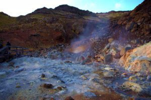 Eine Gruppe von Menschen steht in der Nähe einer heißen Quelle in Island.