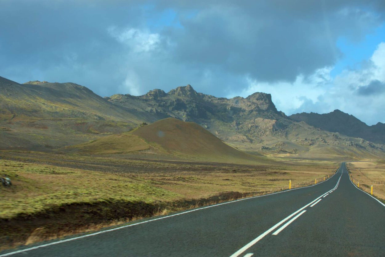 Eine Straße in Island mit Bergen im Hintergrund.