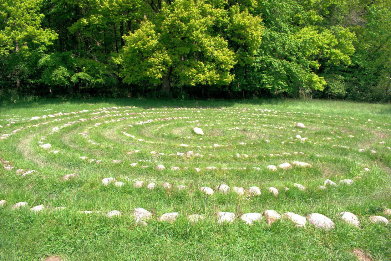 Ein kreisförmiges Steinlabyrinth inmitten einer Wiese.