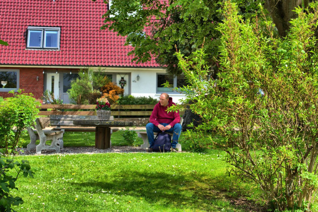 Eine Frau sitzt auf einer Bank vor einem Haus.