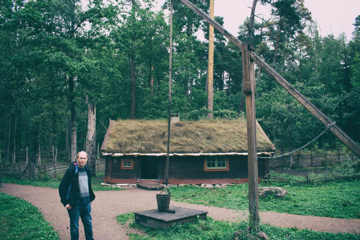 Ein Mann steht vor einer Holzhütte im Wald.