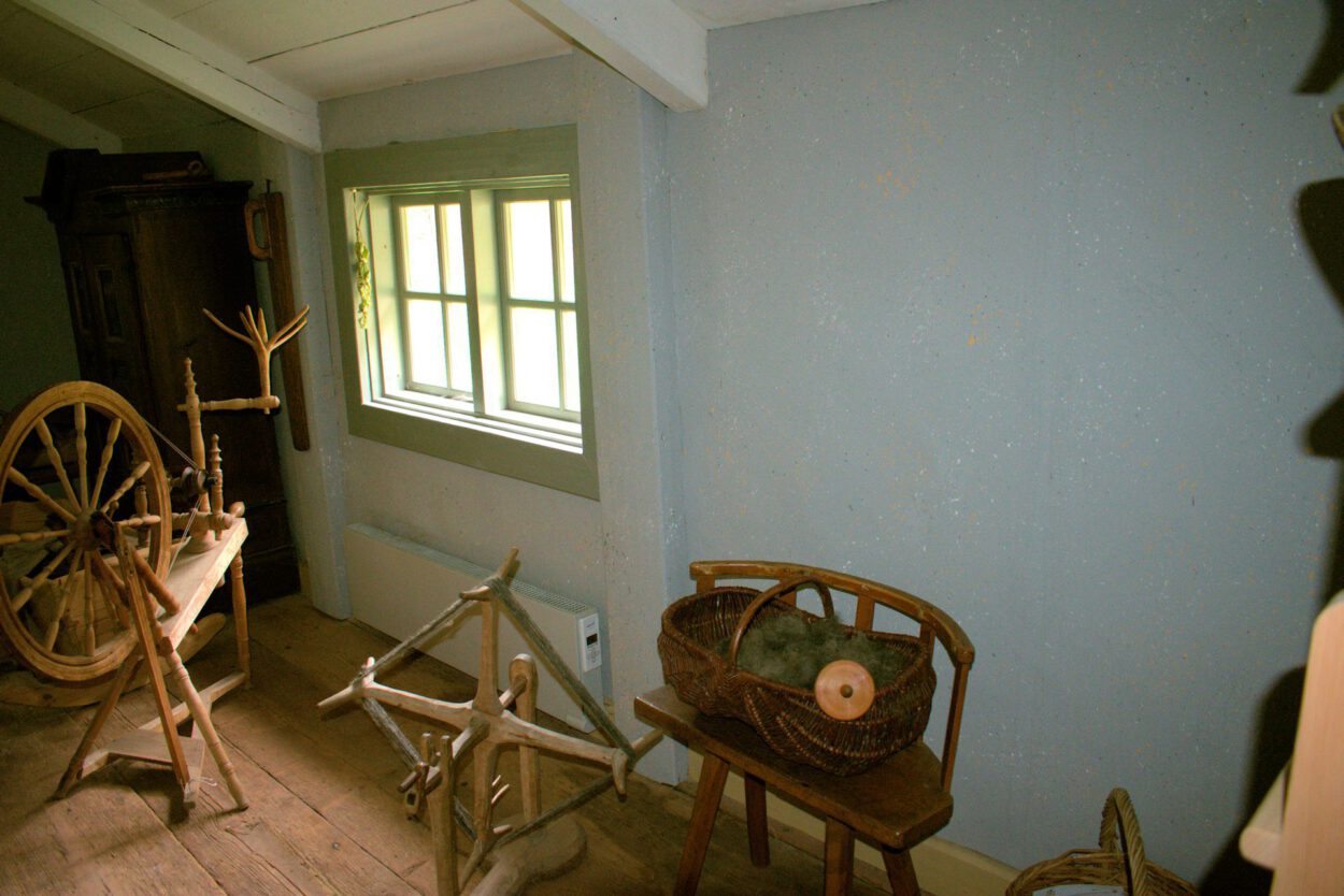 Ein Raum mit einem Spinnrad und einem Fenster.