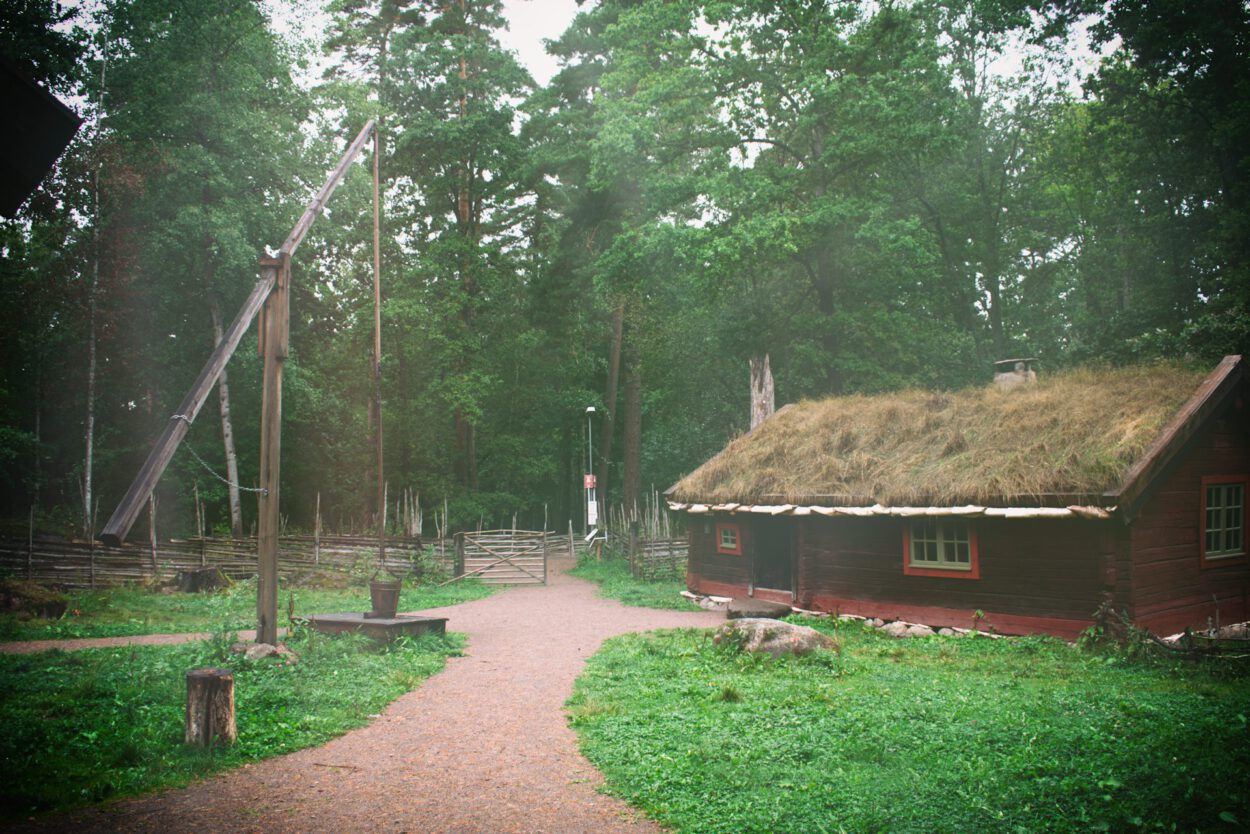 Eine Holzhütte mit Grasdach im Wald.