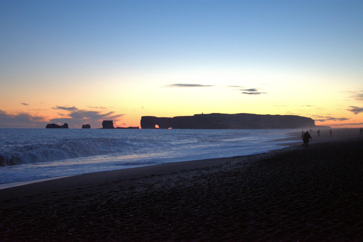 Eine Person, die bei Sonnenuntergang am Strand spaziert.