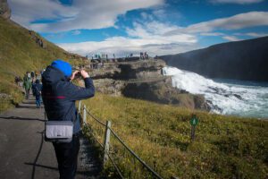 Ein Mann fotografiert einen Wasserfall in Island.