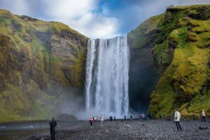 Eine Gruppe von Menschen steht in der Nähe eines Wasserfalls in Island.