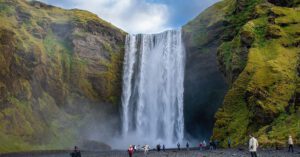 Eine Gruppe von Menschen steht in der Nähe eines Wasserfalls in Island.
