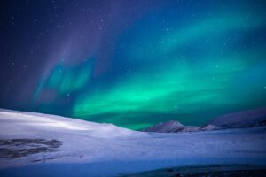 Die Aurora Borealis über einer verschneiten Landschaft.
