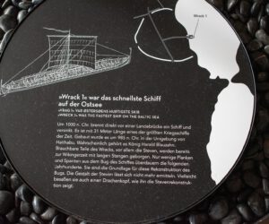 Eine Gedenktafel mit dem Bild eines Schiffes darauf.