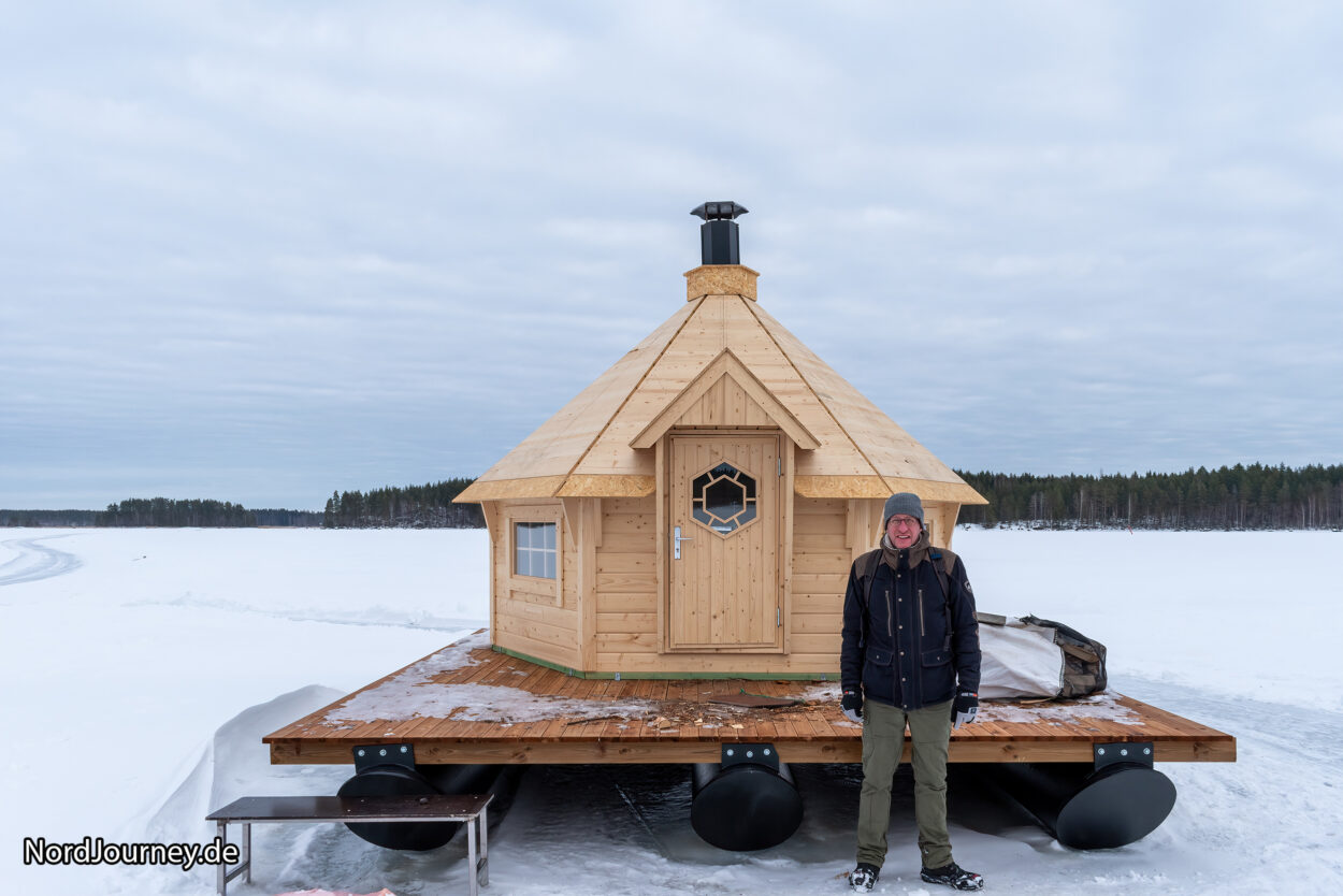 Ein Mann steht vor einer Holzhütte auf einem Boot.