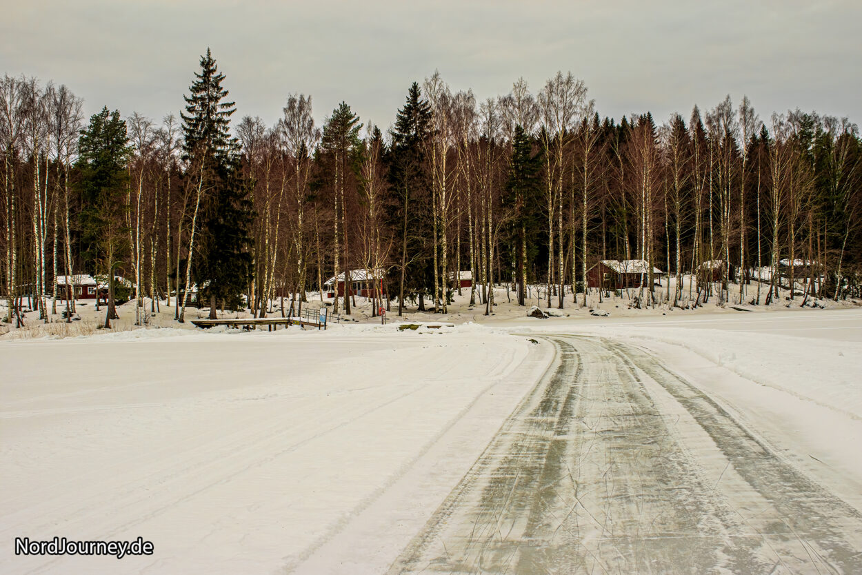 Eine schneebedeckte Straße in einem Waldgebiet.