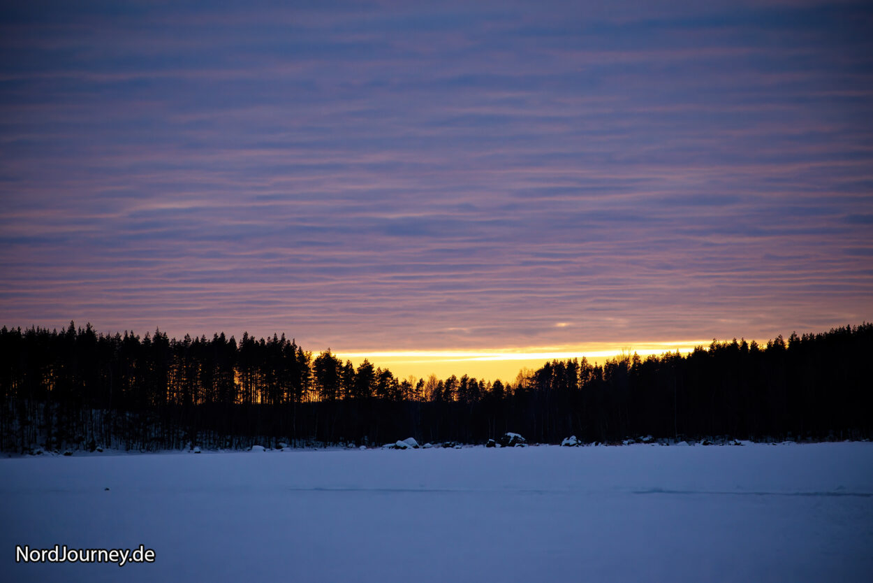 Ein schneebedecktes Feld bei Sonnenuntergang.