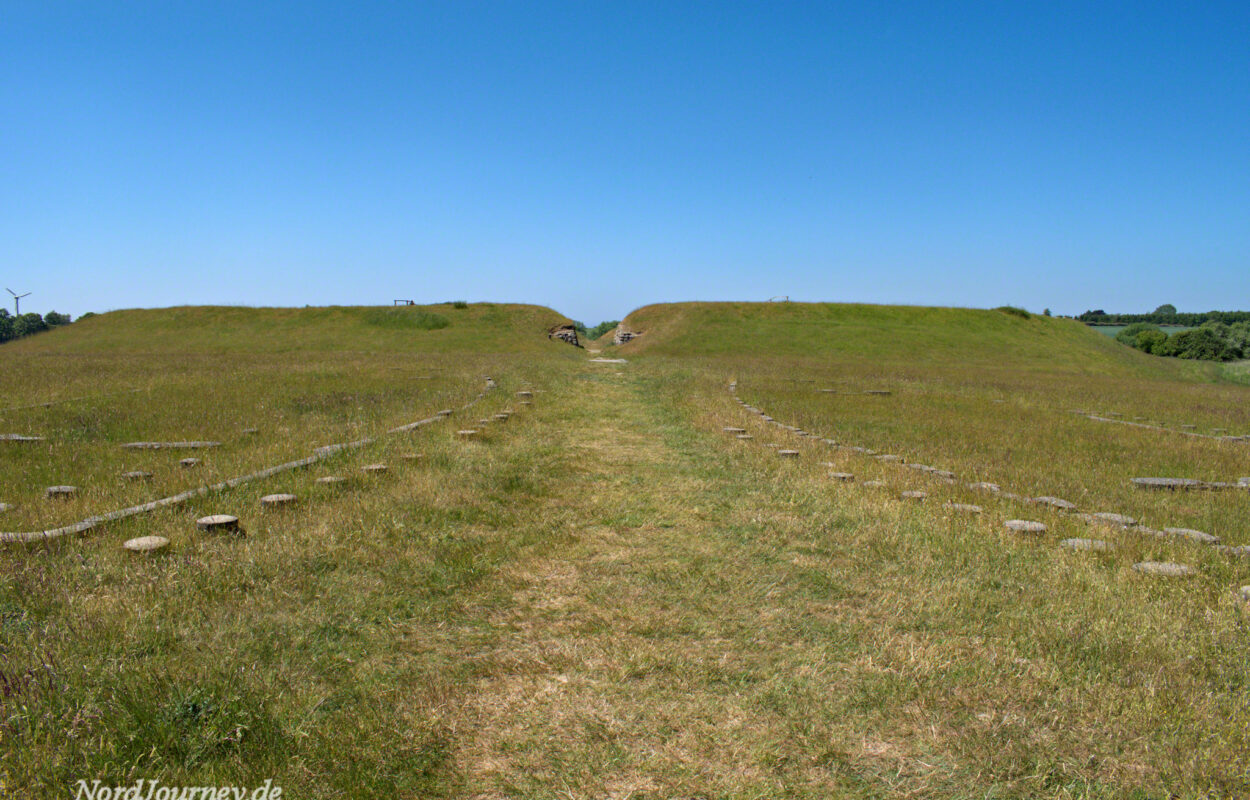Ein grasbewachsenes Feld mit einem Weg, der zu einem Hügel führt.