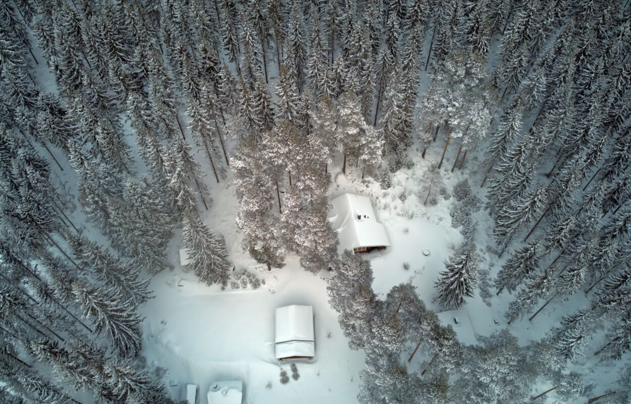 Eine Luftaufnahme eines Hauses in einem verschneiten Wald.
