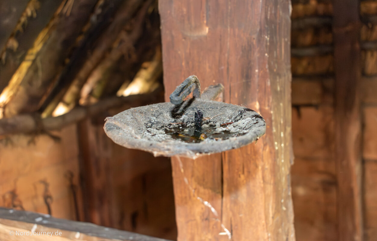Ein hölzernes Waschbecken in einer Hütte mit Holzdach.