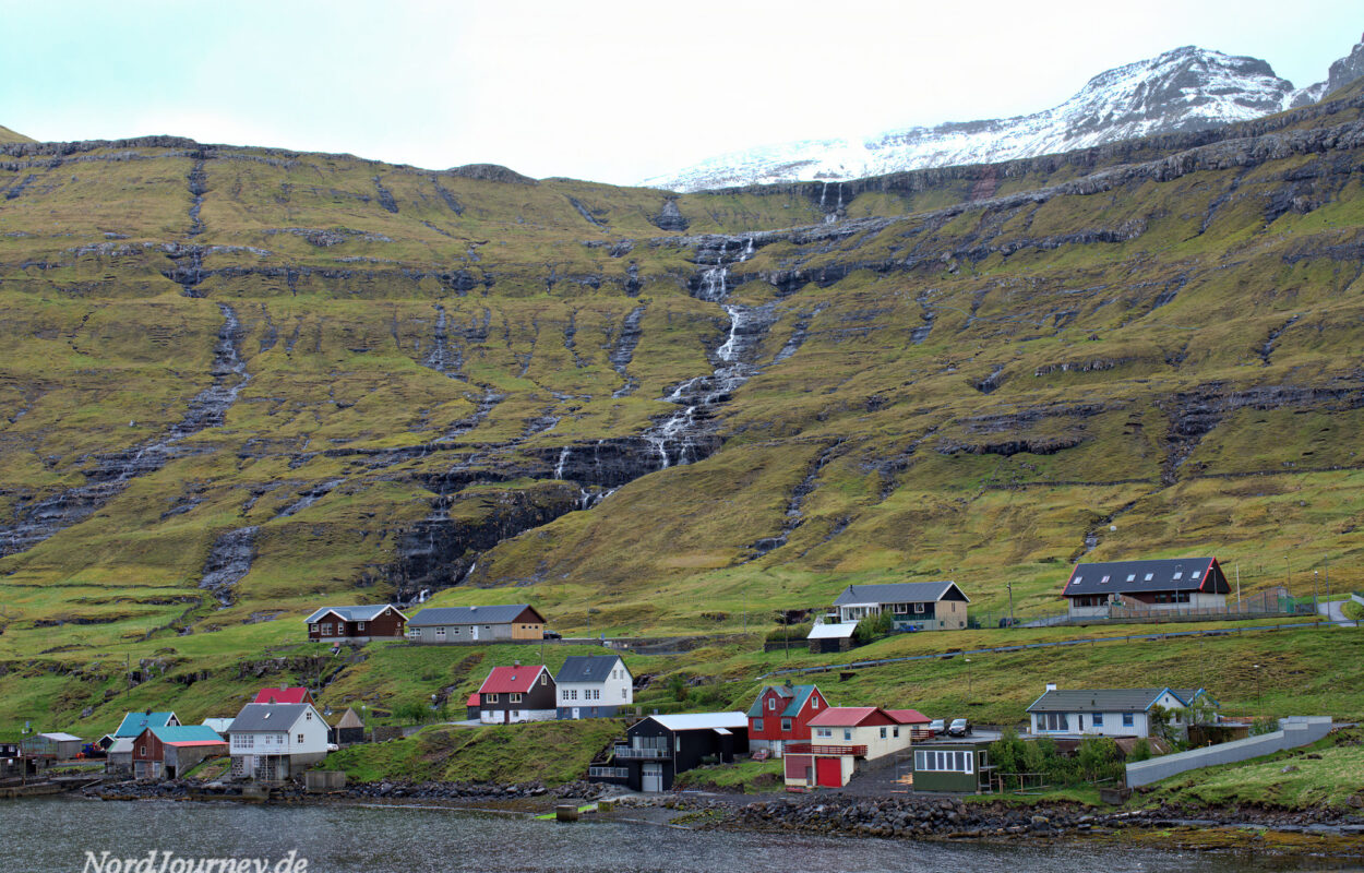Ein Dorf am Hang eines Berges mit einem Wasserfall.