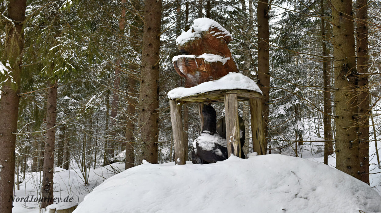 Eine Bärenstatue in einem schneebedeckten Waldgebiet.