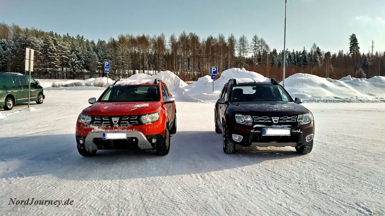 Zwei rote und schwarze SUVs parkten im Schnee.