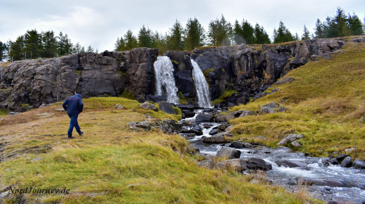 Ein Mann steht vor einem Wasserfall.