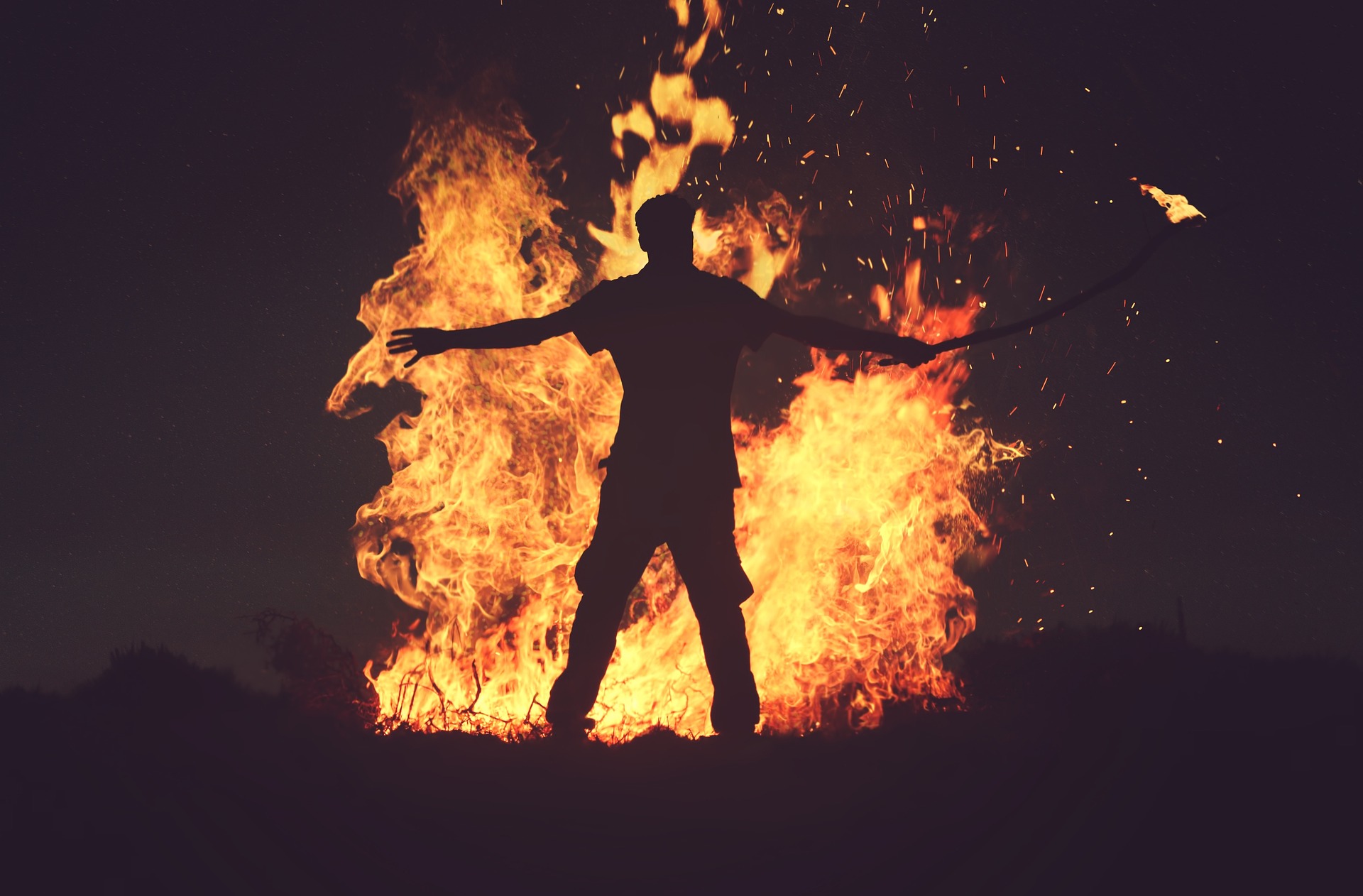 Die Silhouette eines Mannes, der vor einem Feuer steht und von der Faszination skandinavischer Musik fasziniert ist.