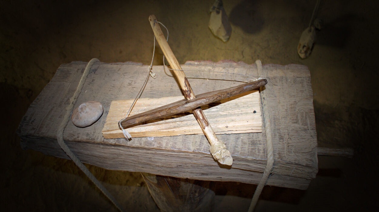 Auf einem Holzblock ist ein primitiver Feuerbohrer ausgestellt, zusammen mit einem Stein und einem Seil, wie er in der Antike häufig zum Feuermachen verwendet wurde.